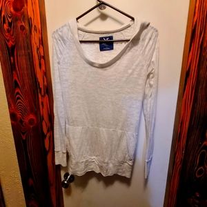 White long sleeve hooded Tee shirt with pocket for hands on front.
